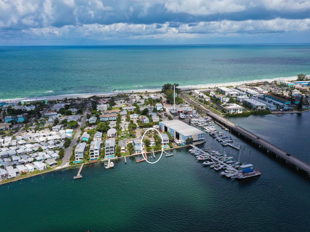 Stunning aerial view showcases waterfront properties nestled between pristine beaches and protected marina, offering the perfect coastal getaway location.