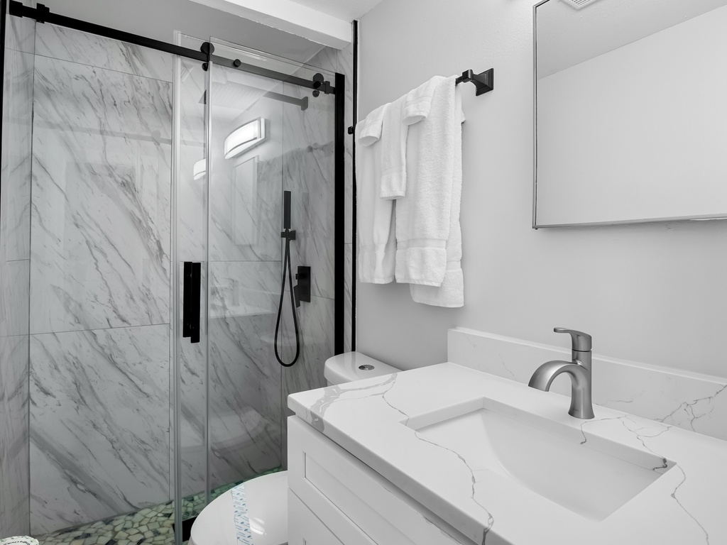 Bright bathroom with walk-in shower and fresh towels provided.