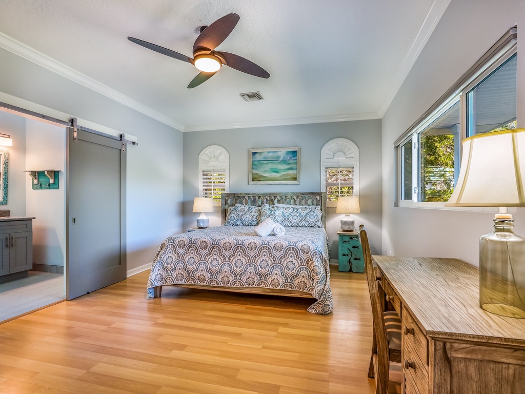 Unwind in your serene master bedroom with warm hardwood floors, coastal artwork, and sliding barn doors opening to your private ensuite bathroom.