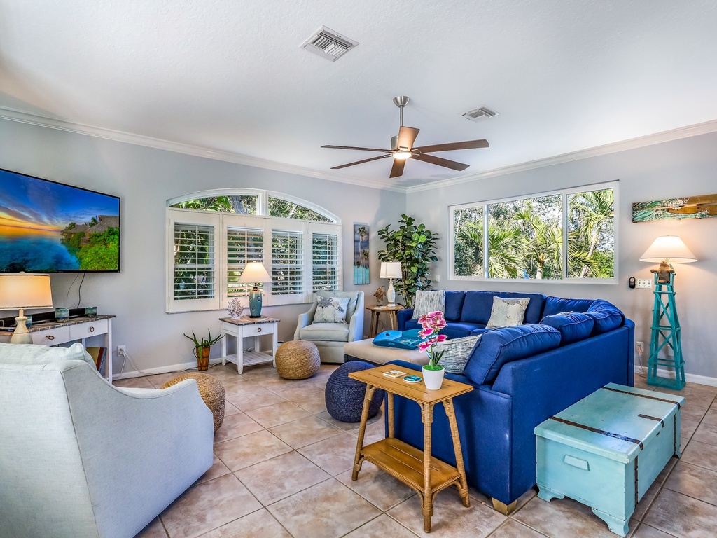 Relax in your spacious living room with plush seating, tropical views through large windows, and modern entertainment.
