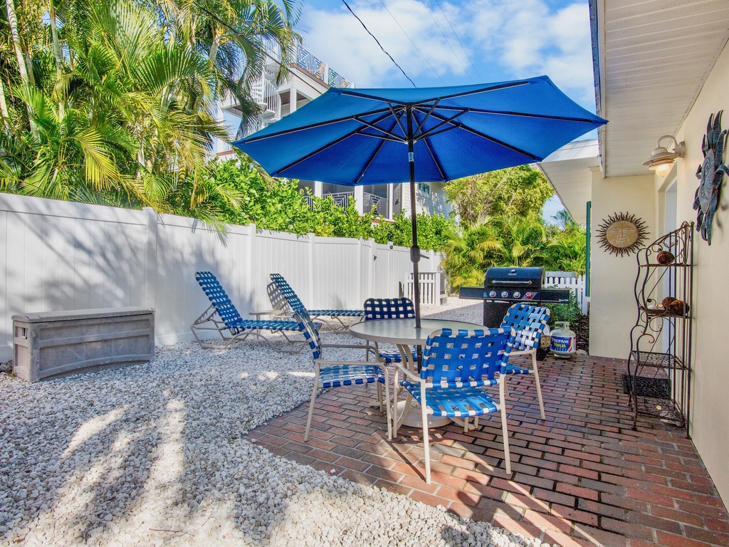 Your private patio features comfortable seating, a BBQ grill, and tropical palm views - perfect for outdoor dining and relaxation in the Florida sunshine.
