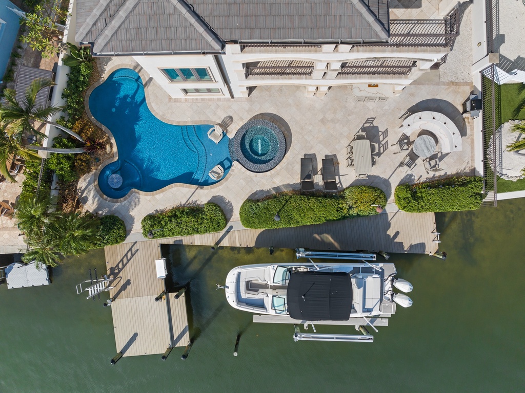Aerial view of waterfront villa with sparkling pool, private boat dock