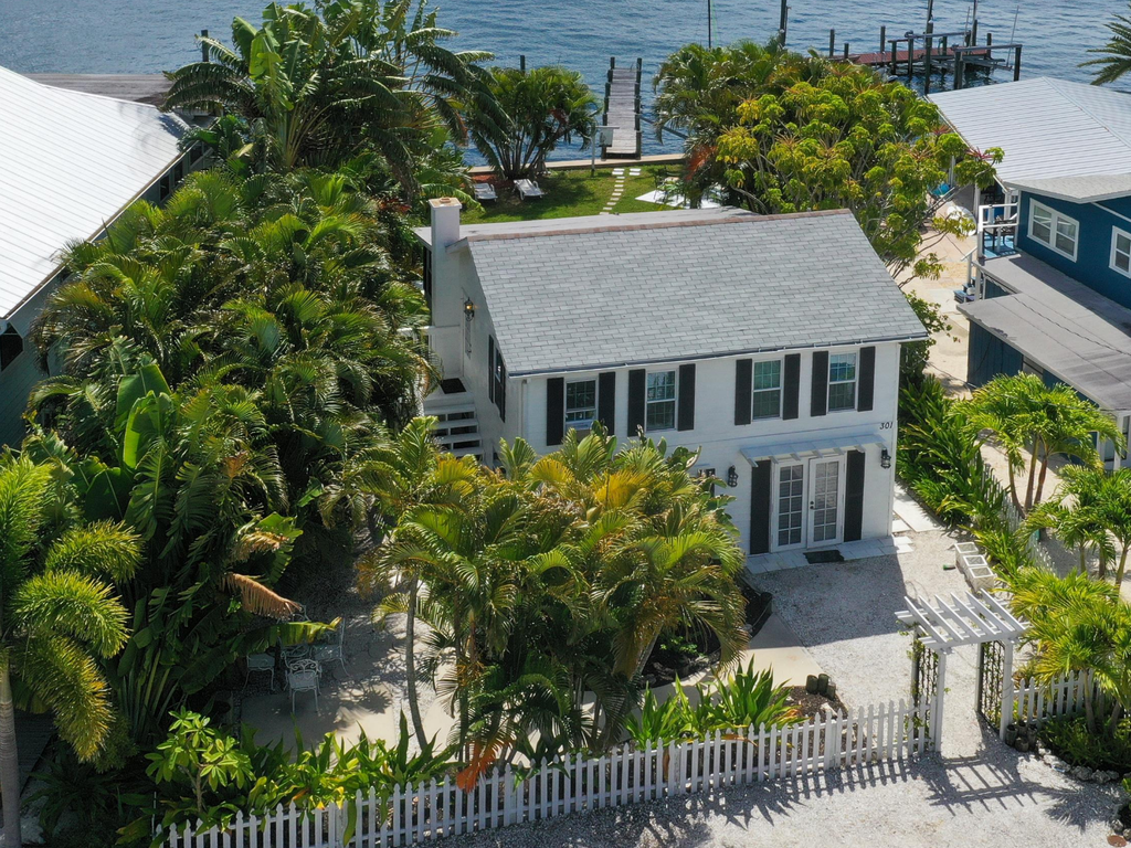 Charming waterfront property surrounded by tropical palms with private dock access and pristine landscaping in a peaceful coastal setting.