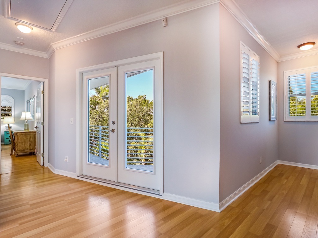 Step onto your private balcony through gleaming French doors, where warm hardwood floors and soft natural light create the perfect retreat.