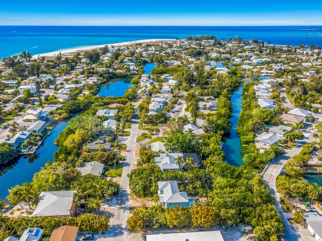 Stunning aerial view of a waterfront community featuring turquoise canals winding through tropical homes near pristine beaches.