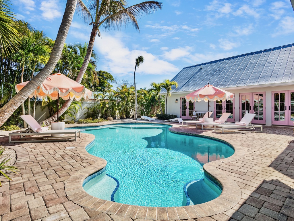 Private tropical oasis with pool surrounded by swaying palms and comfortable loungers