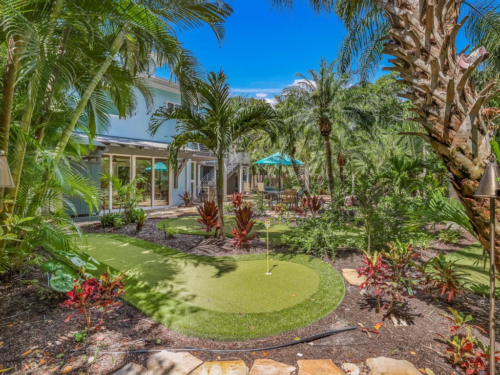 Tropical paradise with lush palm trees, vibrant landscaping, and your own private putting green surrounded by colorful gardens.
