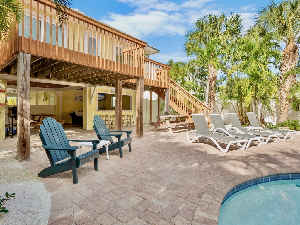 Tropical paradise awaits with your private pool deck featuring Adirondack chairs and sun loungers beneath swaying palms.