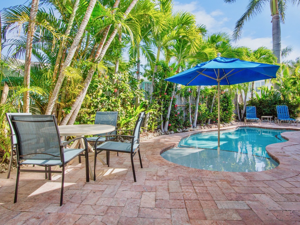 Relax by your private tropical pool surrounded by swaying palm trees, with comfortable poolside seating and shade umbrellas for the perfect vacation retreat.