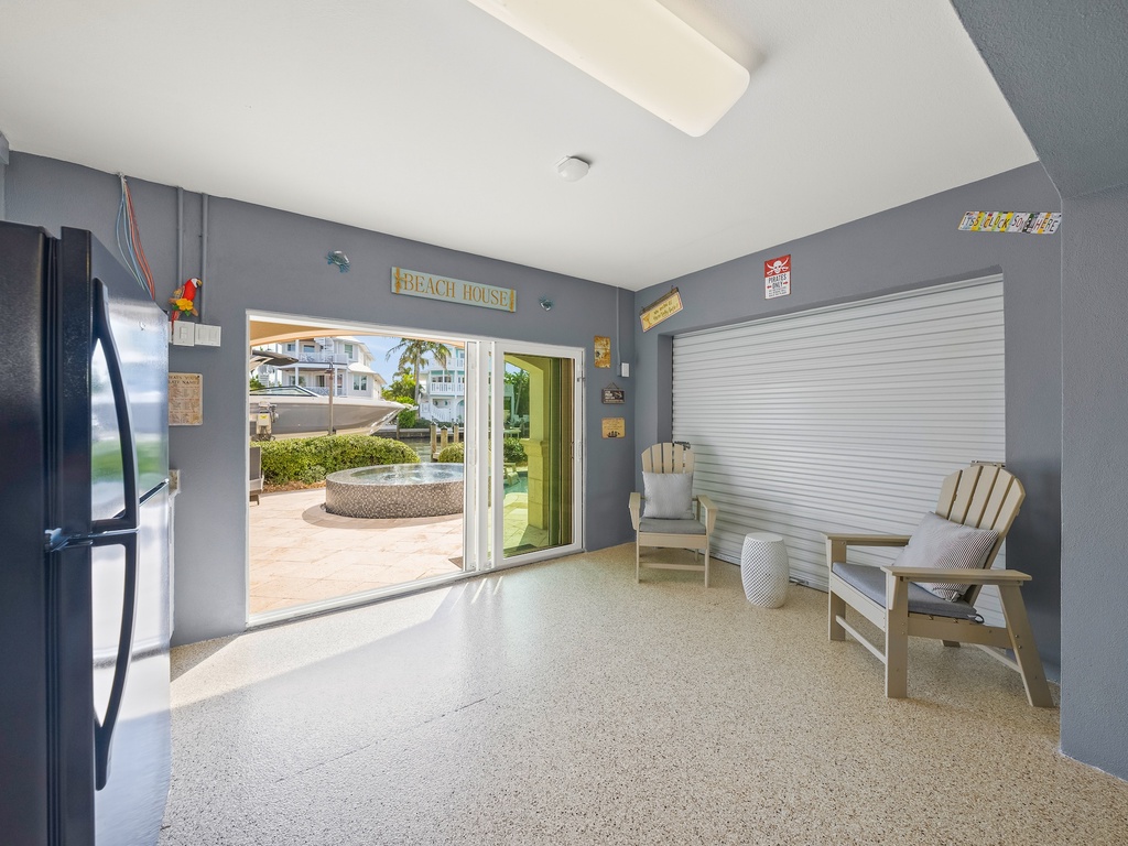 Covered garage opens to tropical views, with comfy seating and a full-size fridge