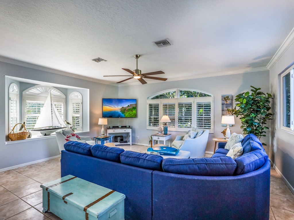 Sink into plush blue seating while cool ceiling fans circulate fresh air through your bright, airy living space with garden views.