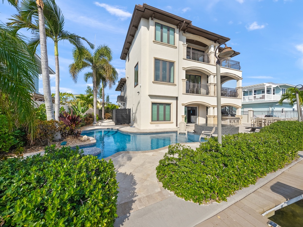 Waterfront villa with pristine pool, tropical palms, and multiple balconies overlooking the canal
