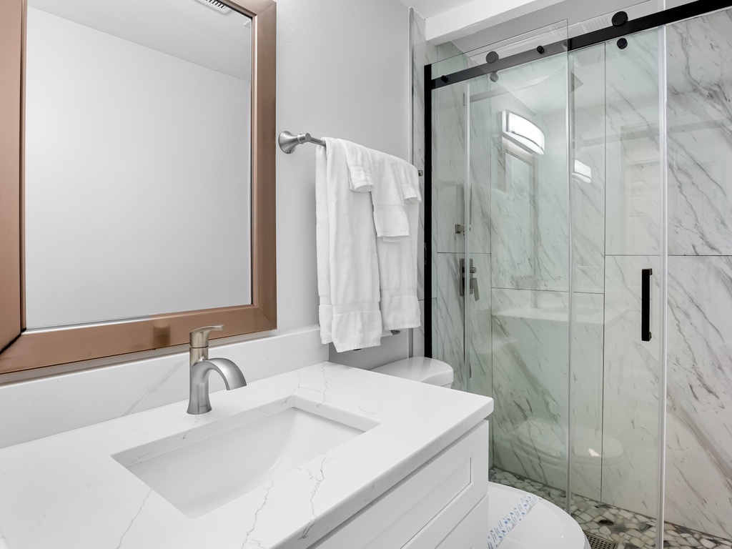 Bright bathroom with walk-in shower and fresh towels provided.