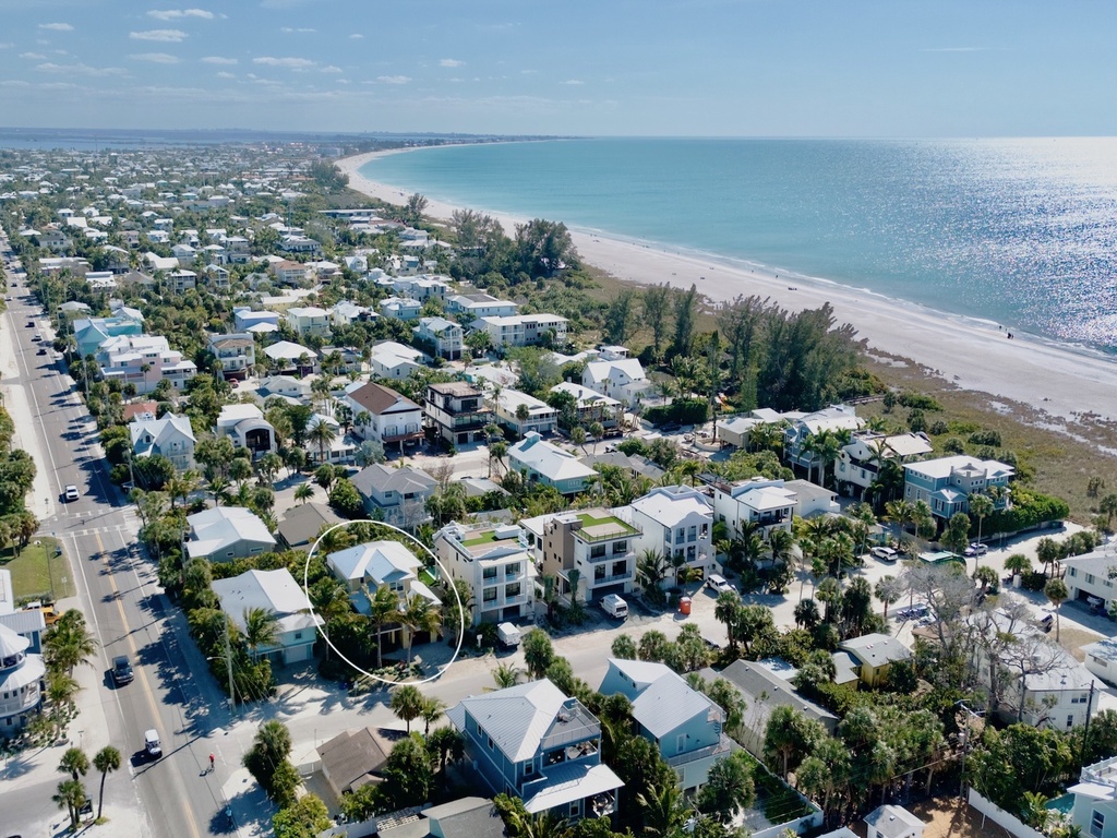 Beachfront community with pristine white sand beach and turquoise waters stretching to the horizon.