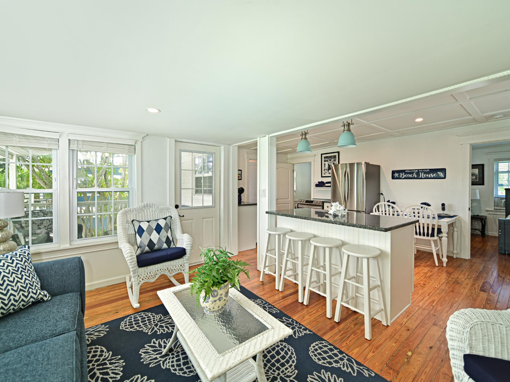 Relax in your stylish open-plan living space where coastal charm meets modern comfort, complete with a fully equipped kitchen and cozy seating.