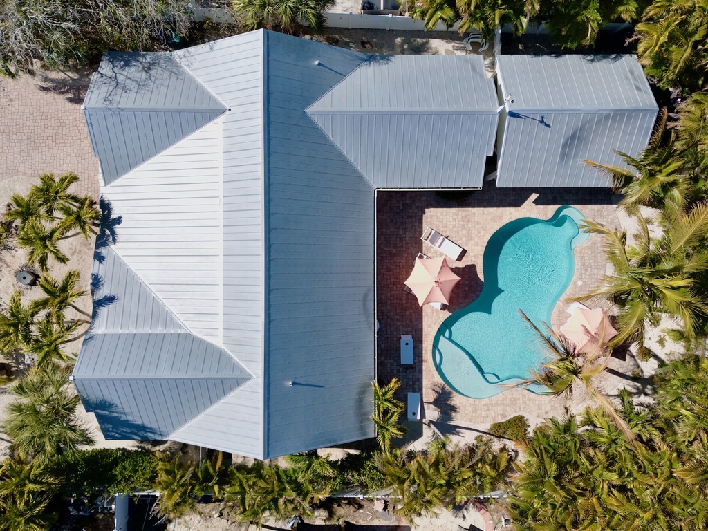 Stunning beachfront property featuring a crystal-clear pool surrounded by swaying palms and pristine sandy shores.