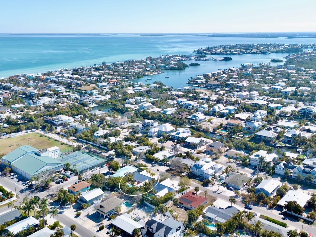 Aerial view of a charming coastal community with pristine turquoise waters and residential neighborhoods nestled between beaches and inland waterways.