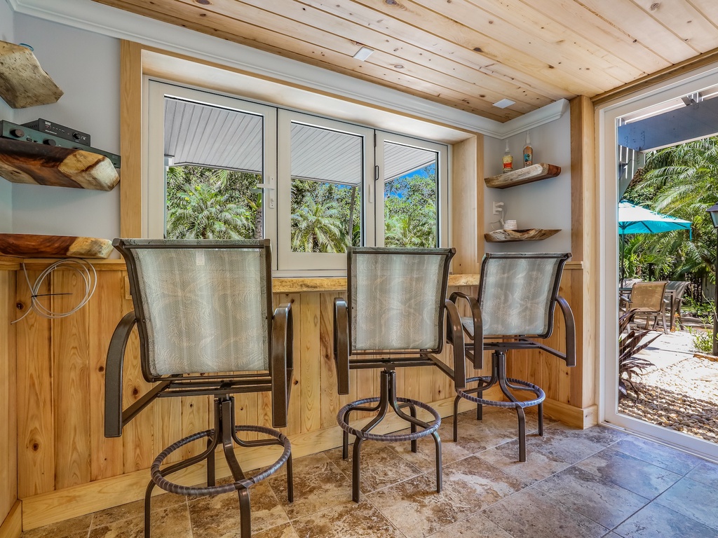 Sip your morning coffee at this tropical breakfast bar with garden views and rustic wood beams overhead.