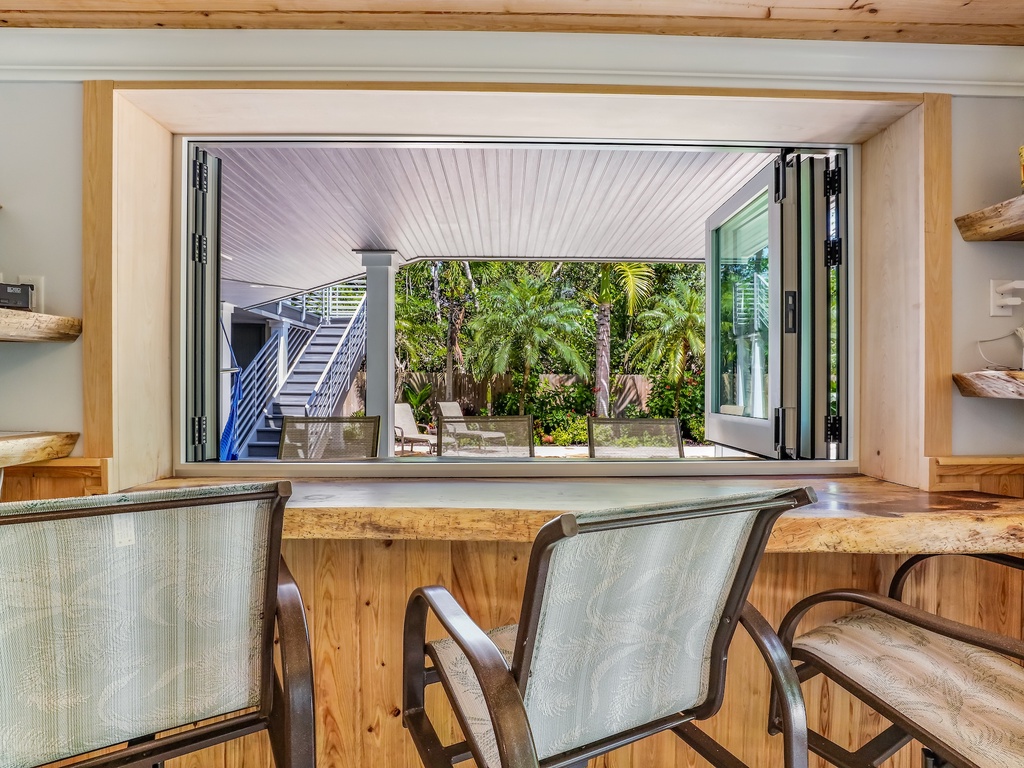 Enjoy meals at your rustic dining table while folding doors open to reveal tropical gardens and outdoor stairs.