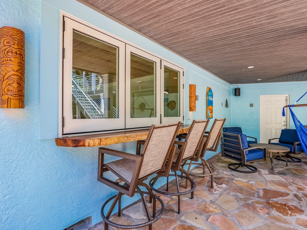 Your tropical-themed patio awaits with tiki bar seating and vibrant turquoise walls, perfect for evening cocktails and relaxation.