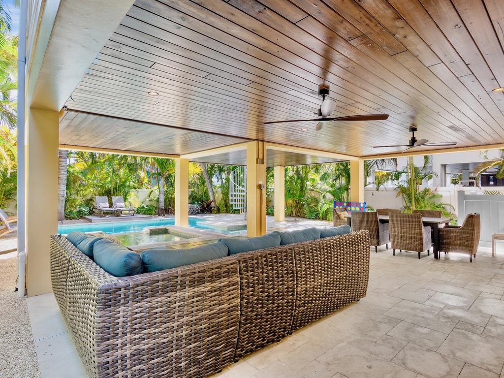 Your tropical oasis awaits with elegant covered living, where plush seating faces the sparkling pool amid swaying palms.
