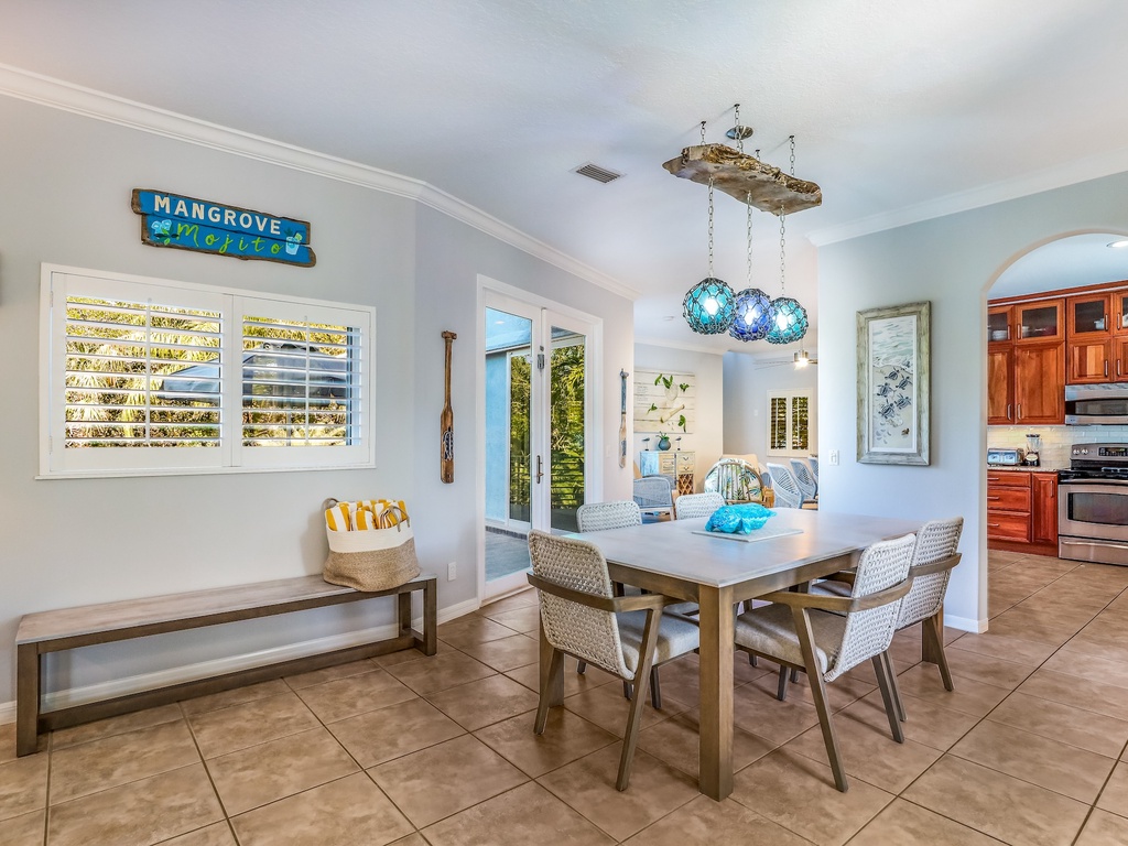 Gather around your bright dining table where coastal breezes flow through plantation shutters and tropical touches create the perfect breakfast spot.
