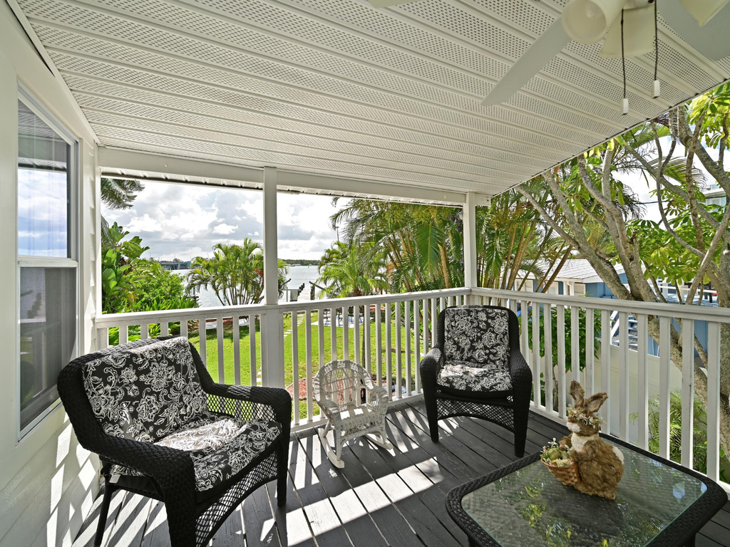 Relax in your private covered balcony with comfortable wicker seating and peaceful water views through tropical foliage.