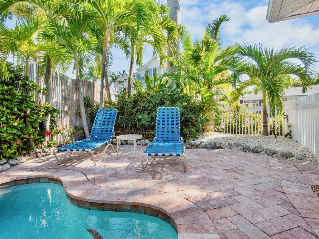 Relax by your private pool surrounded by tropical palms and comfortable lounge chairs on a sunny paver deck.
