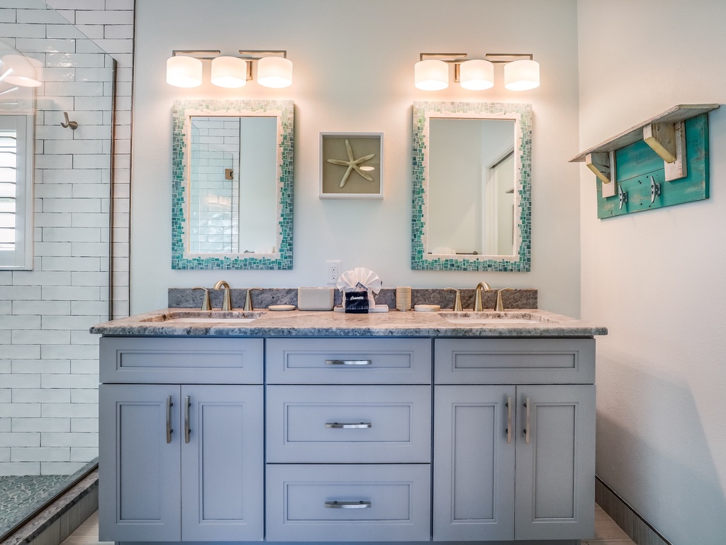 Step into your elegant master bathroom featuring double vanities with granite countertops and beautiful teal-tiled mirrors that catch the morning light perfectly.