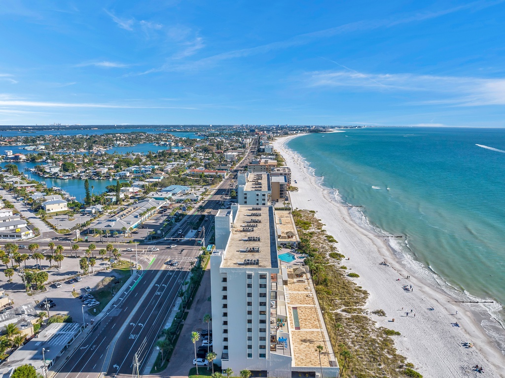 Stunning aerial view of beachfront property with pristine white sand beaches and crystal-clear turquoise waters stretching to the horizon.