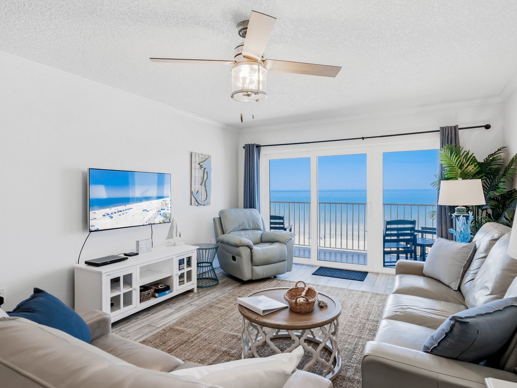 Your coastal living room opens to stunning ocean views through glass doors, while you relax on plush seating with entertainment at your fingertips.