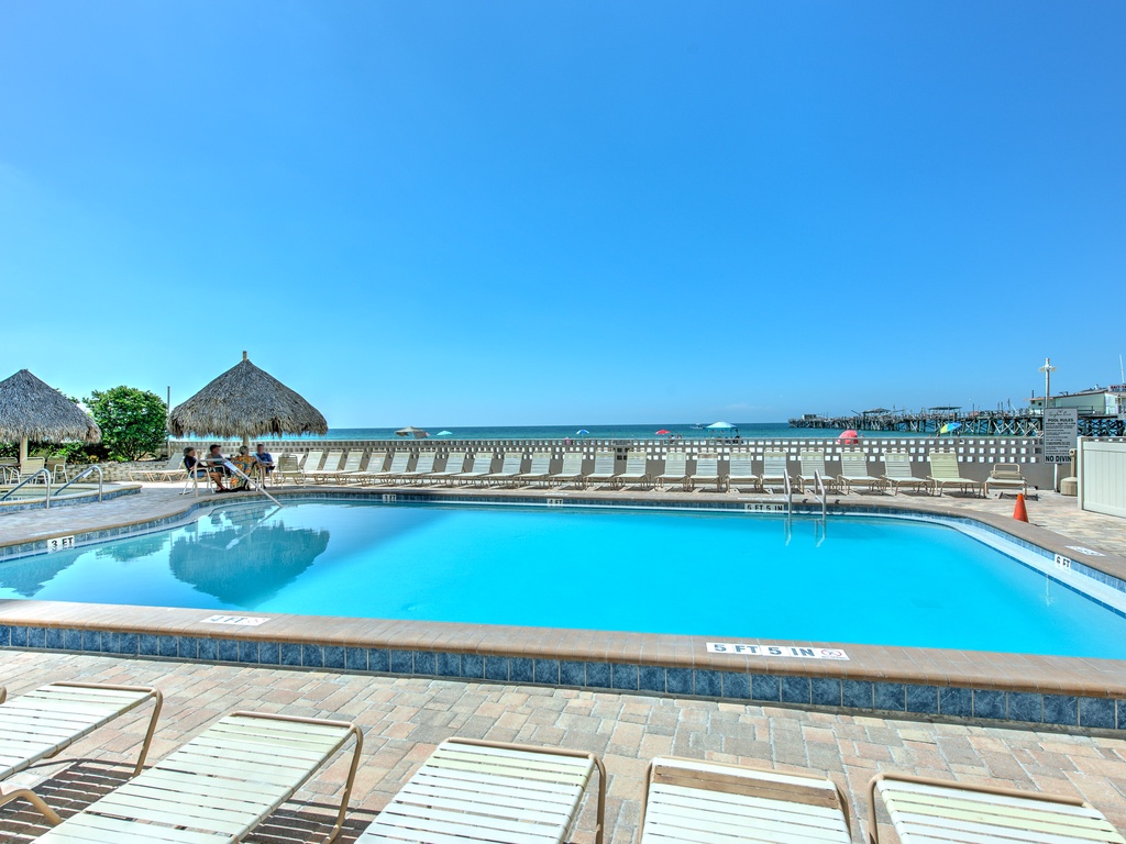 Crystal-clear pool with stunning ocean views and tropical thatched huts creating your perfect waterfront paradise escape.