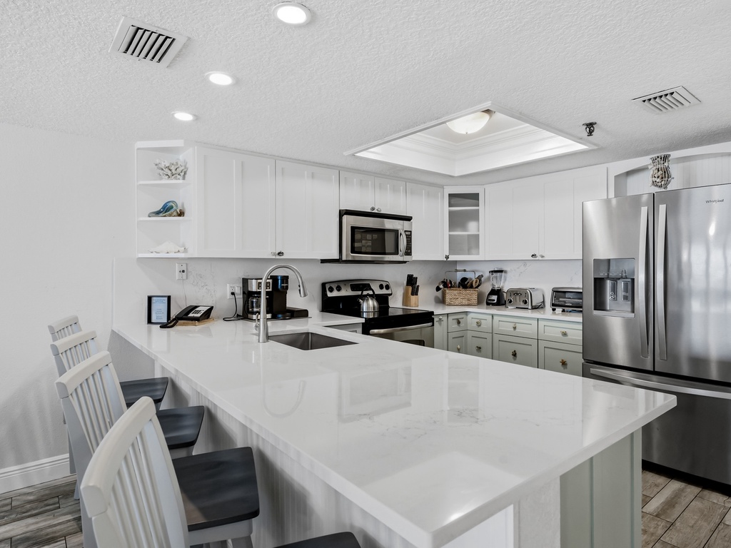 Your fully equipped modern kitchen features sleek white cabinets, stainless steel appliances, and a spacious island perfect for cooking memorable meals.