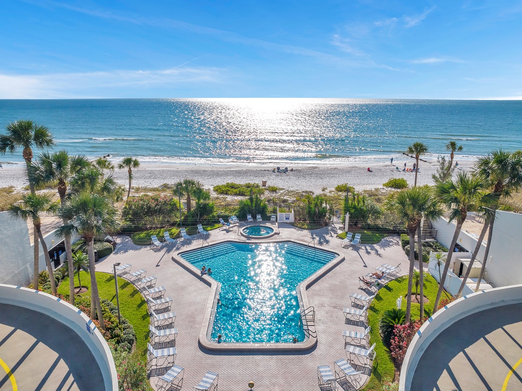 Stunning beachfront property featuring sparkling pools, tropical landscaping, and direct access to pristine sandy shores.