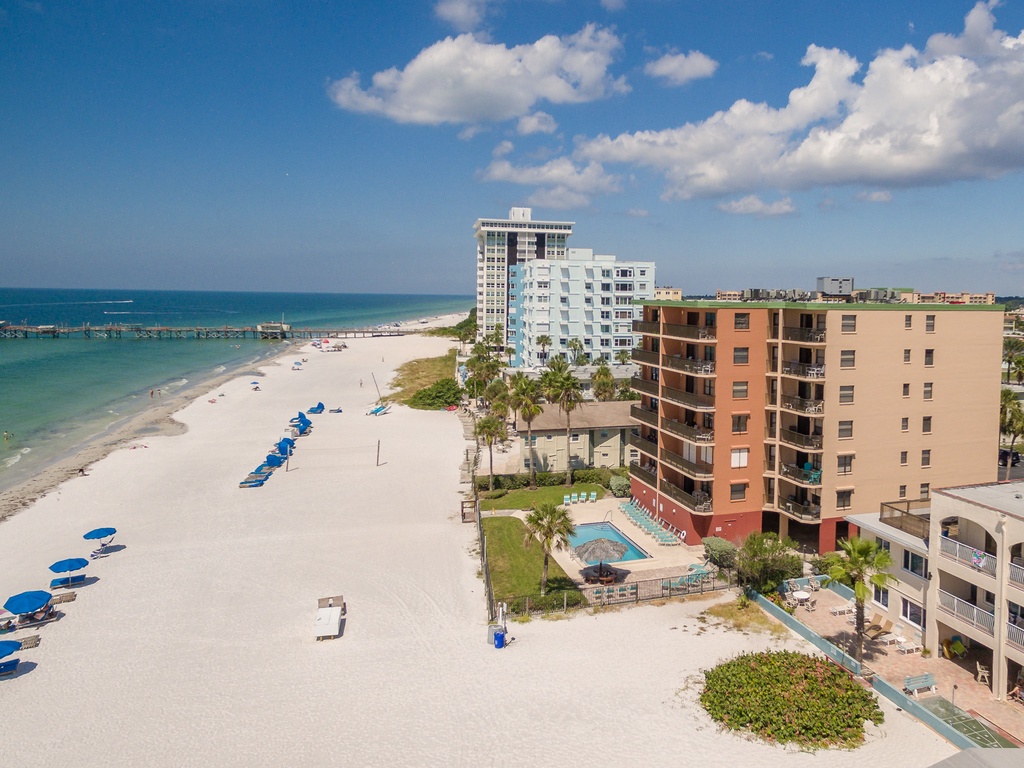 Beachfront buildings and pristine white sand coastline with turquoise waters and resort amenities in a tropical setting.