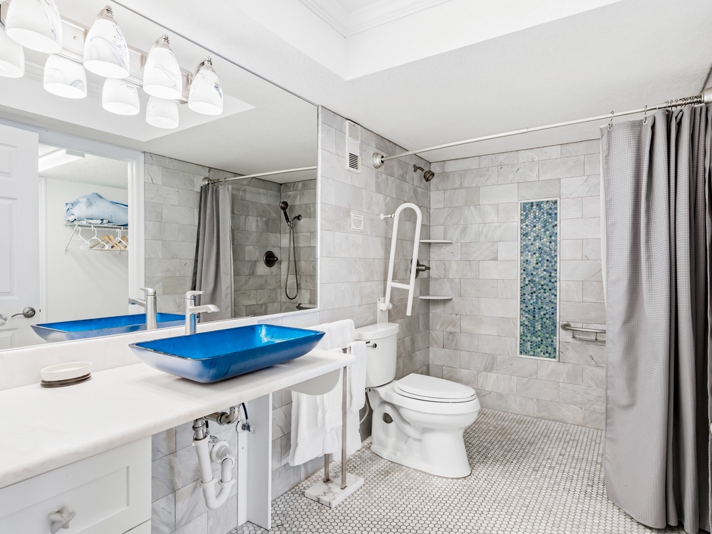 Step into your spa-like retreat with marble tiles, a striking blue vessel sink, and rainfall shower for pure relaxation.