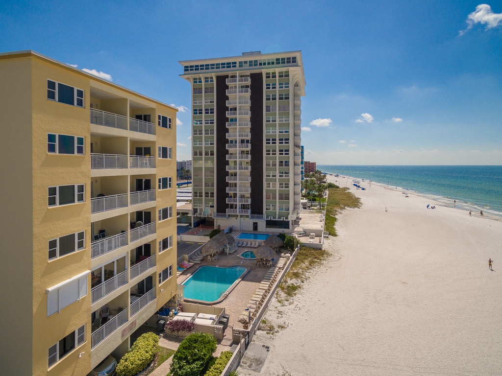 Beachfront property buildings showcase stunning seaside location with direct beach access and pristine white sand stretching along the coastline.