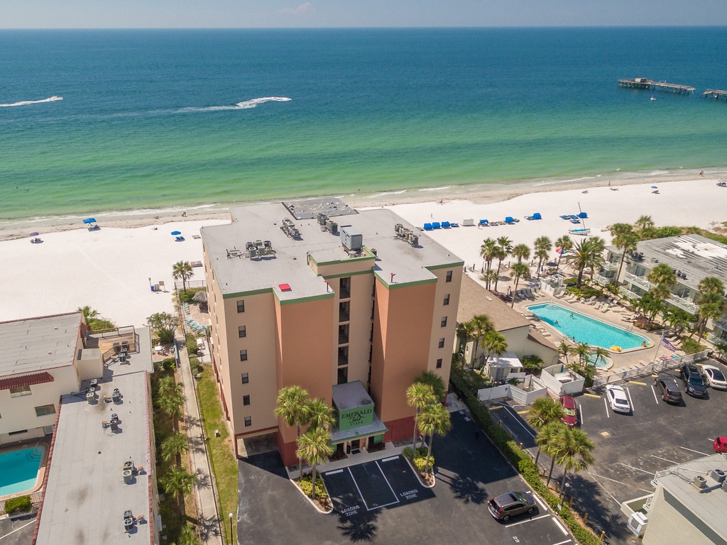 Beachfront property with direct access to pristine white sand beaches and emerald Gulf waters, featuring swimming pool and tropical palm landscaping.