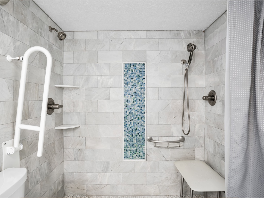 Refresh in your spacious, accessible shower with elegant marble tiles, handheld fixtures, and a beautiful mosaic accent that adds coastal charm.