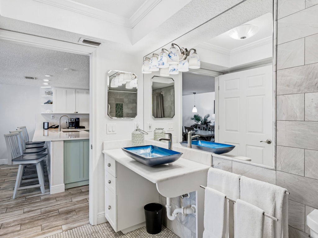 Your elegant dual-sink bathroom features stunning blue vessel bowls and opens beautifully to your bright kitchen space.