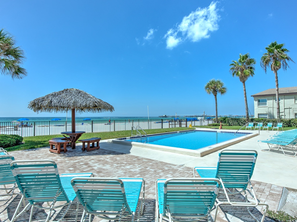 Beachfront pool area features crystal-clear waters, tropical palms, and direct ocean access for the ultimate coastal escape.