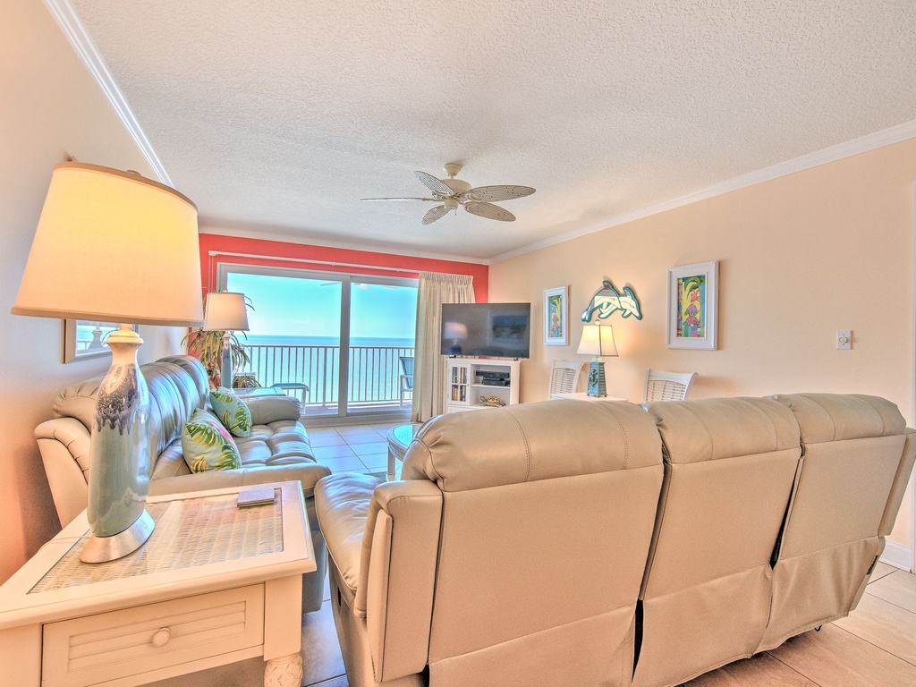 Sink into plush recliners while ocean breezes flow through your coastal living room, where warm peach walls and tropical touches create your perfect seaside retreat.
