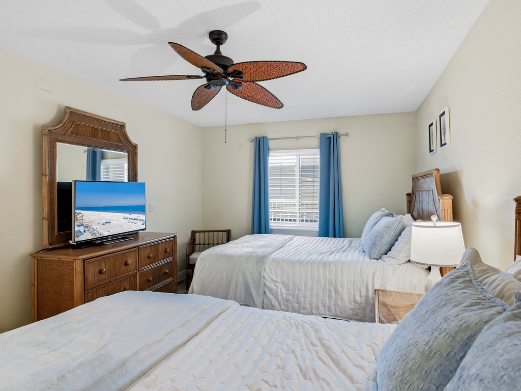 Drift off to peaceful sleep in your coastal-themed bedroom with twin beds, tropical ceiling fan, and beach views on TV.