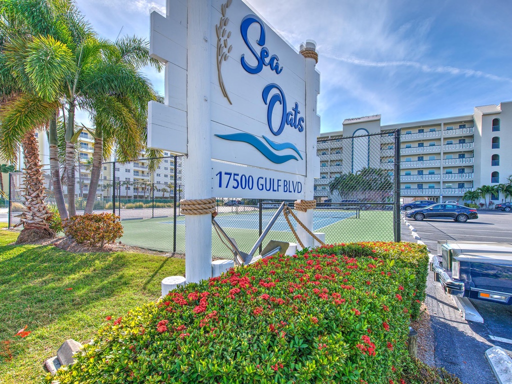 Sea Oats complex entrance sign surrounded by lush tropical landscaping and palm trees, marking your arrival to this beachfront destination.