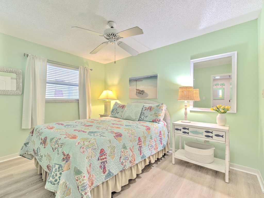 Relax in this charming seafoam bedroom with tropical bedding, warm bedside lighting, and coastal touches that create your perfect beach getaway sanctuary.