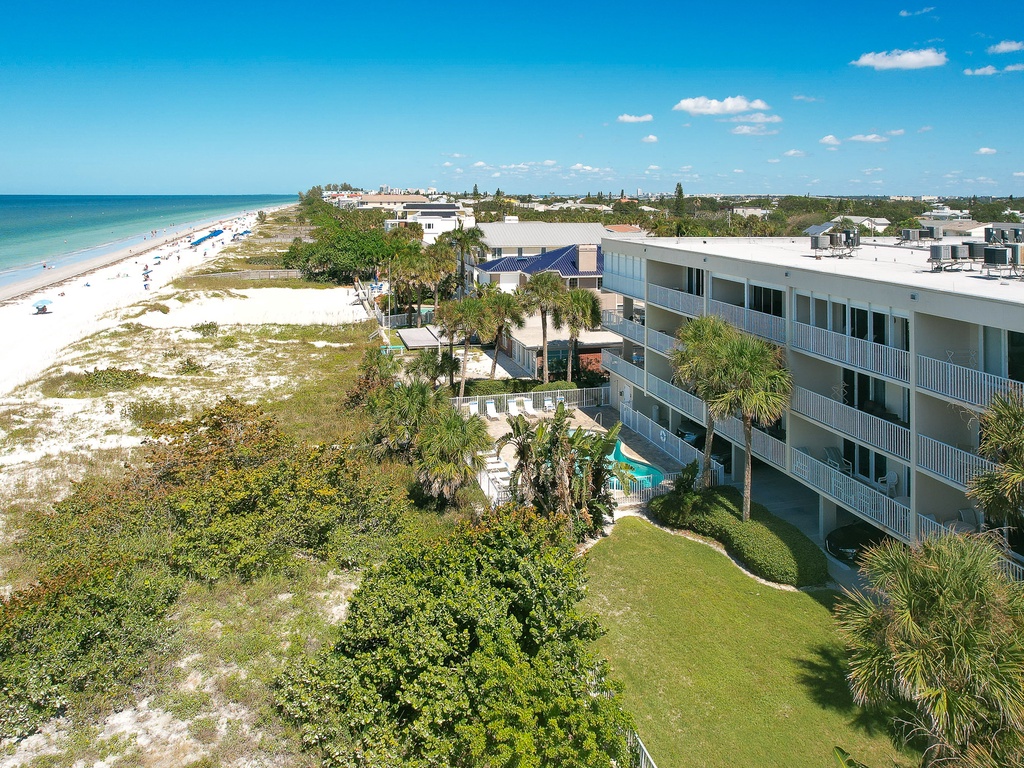 Beachfront property with pristine white sand beaches, tropical landscaping, and multi-story accommodation buildings near the Gulf Coast.