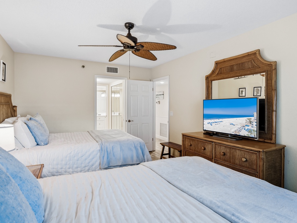 Relax in your tropical-inspired bedroom with twin beds, coastal furnishings, and entertainment center for perfect beach vacation comfort.