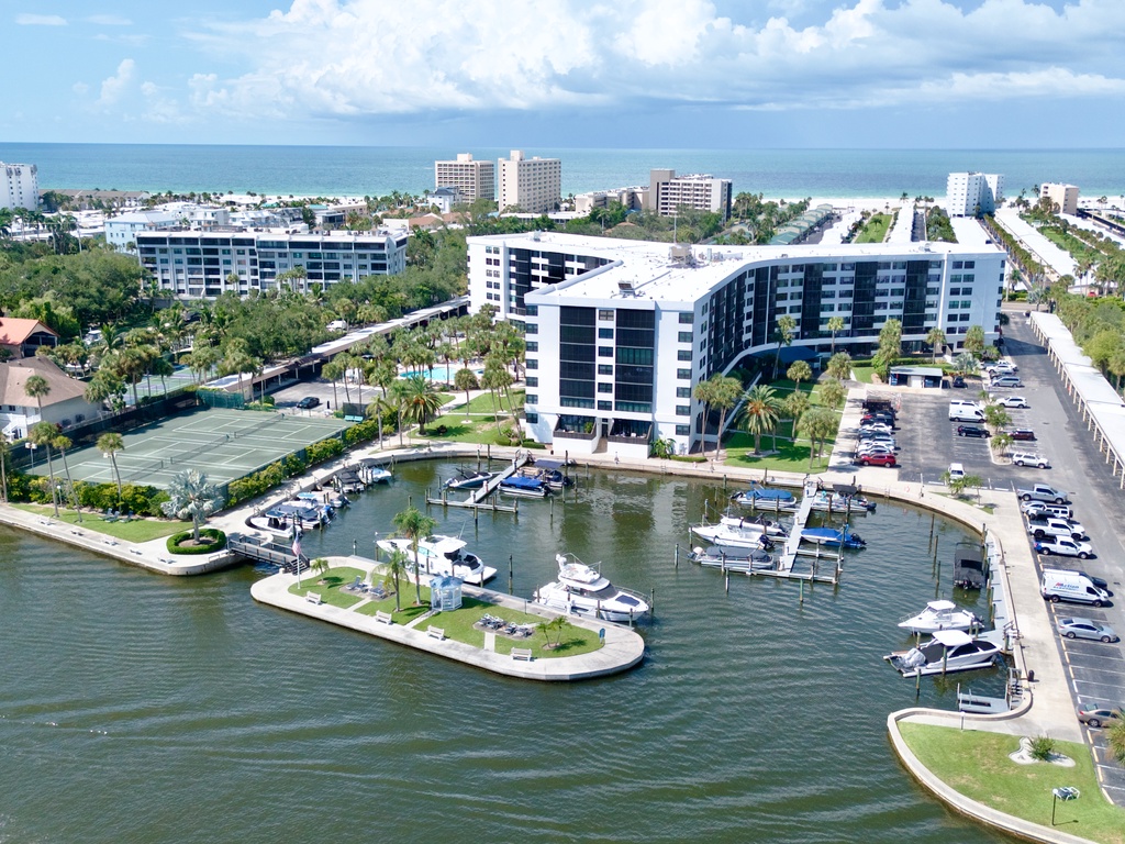 Waterfront community featuring marina access, resort-style buildings, and tropical landscaping near pristine coastal waters.