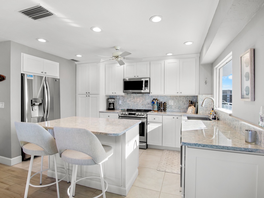 You'll love preparing meals in this bright, modern kitchen with gleaming countertops, stainless steel appliances, and a convenient breakfast bar.