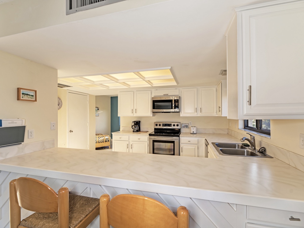 Your fully equipped kitchen awaits with bright white cabinetry, modern appliances, and a breakfast bar where you can start each morning.
